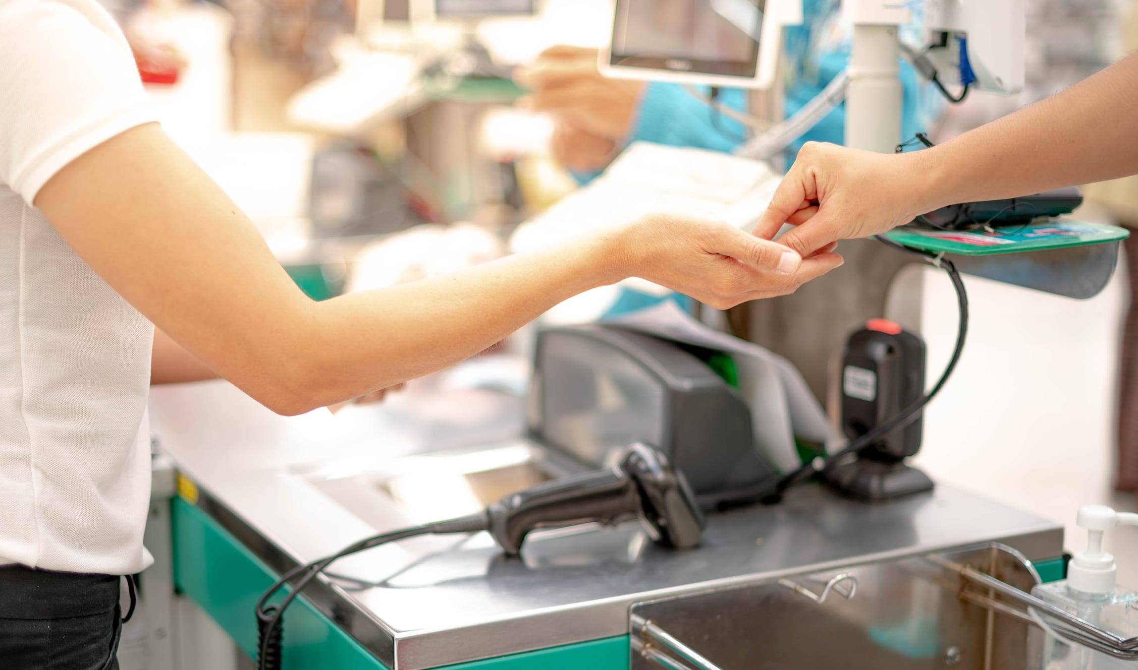 Hand giving cash and hand receiving cash, paying checkout at cashier access in supermarket.